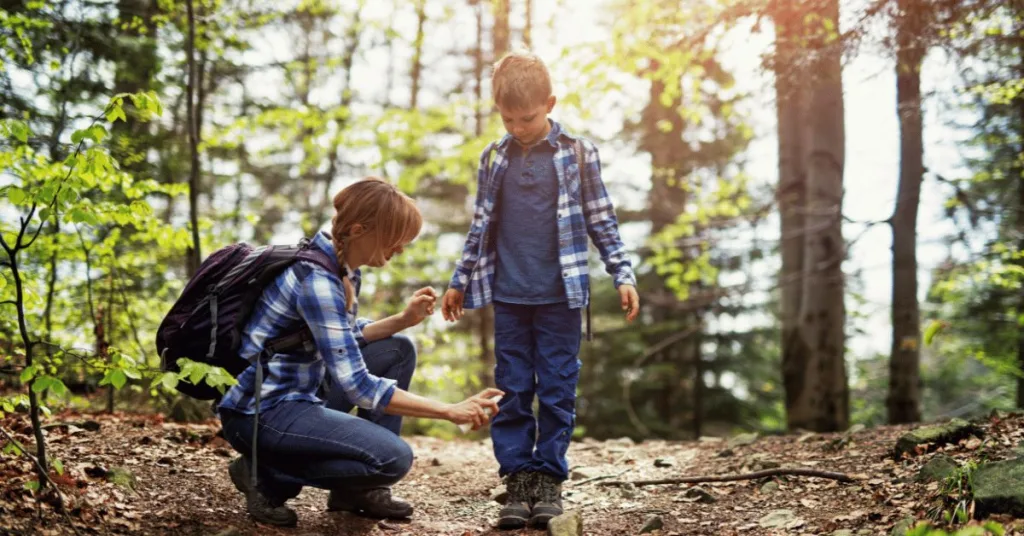 Hikers wearing protective clothing and spaying pesticide to keep ticks away